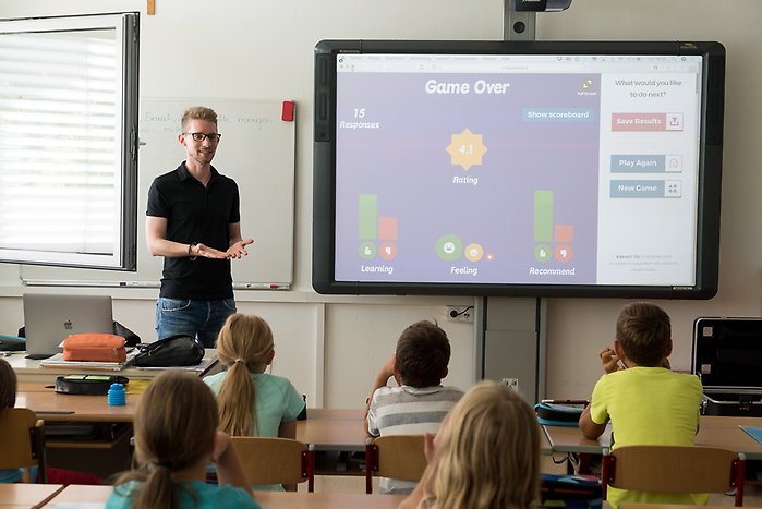 Lärare visar innehåll på interaktiv tavla för skolklass.